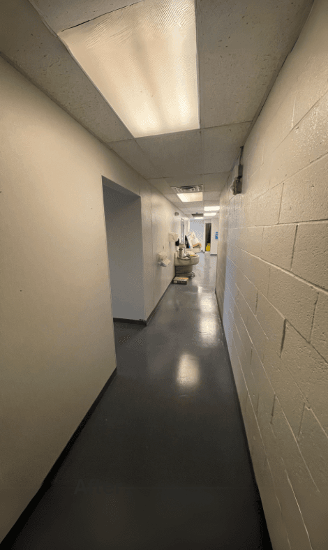 Commercial bathroom hallway after renovation with brighter walls and refreshed flooring.