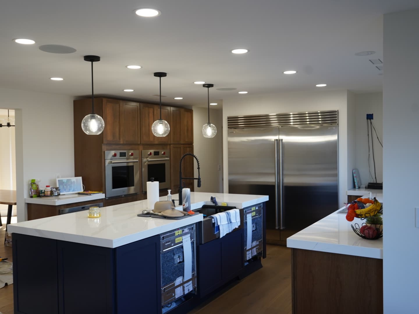Same kitchen after remodel: island, pendant lighting, and appliance wall.