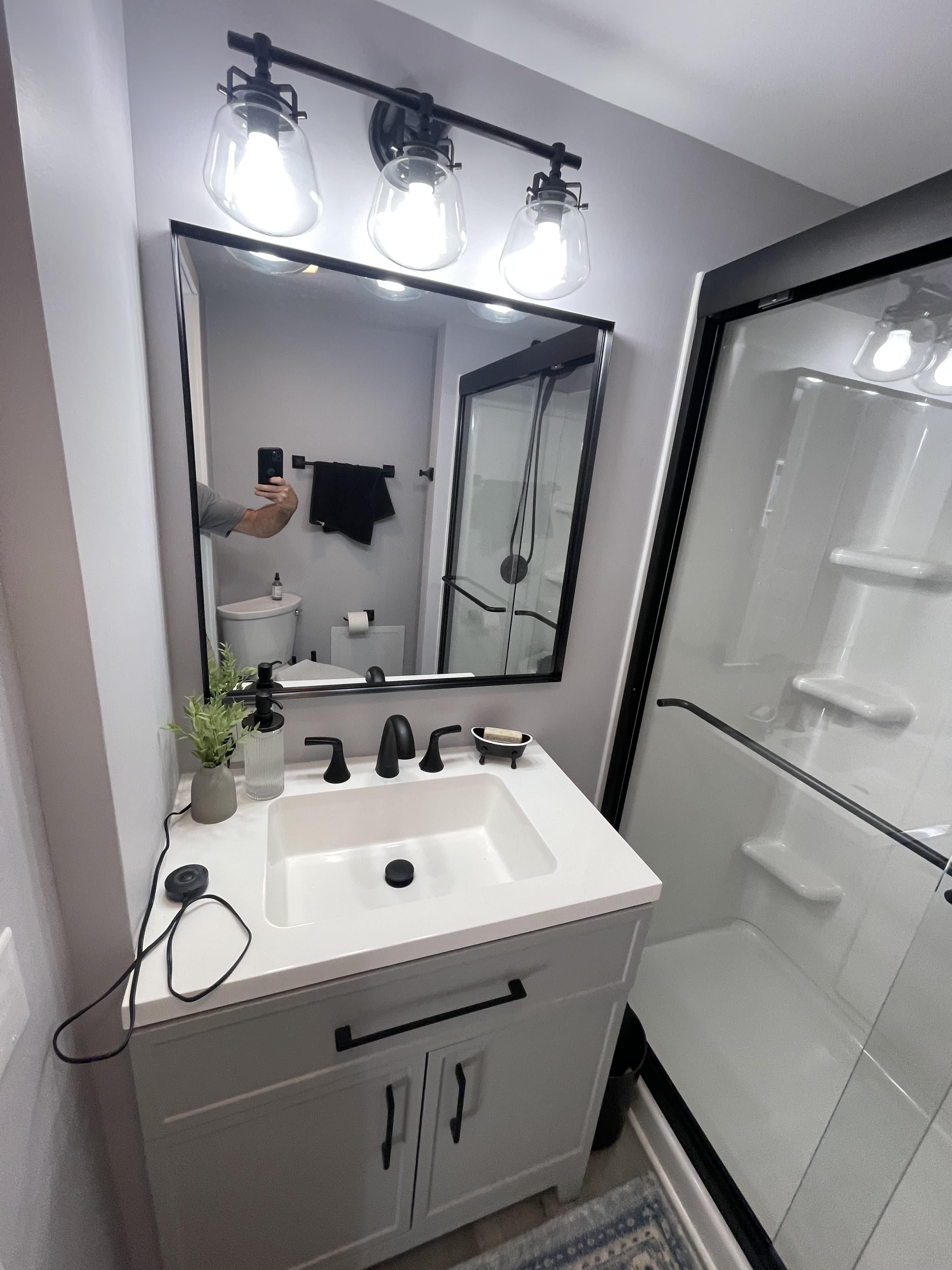 Updated vanity with matte black fixtures, modern mirror, and new lighting