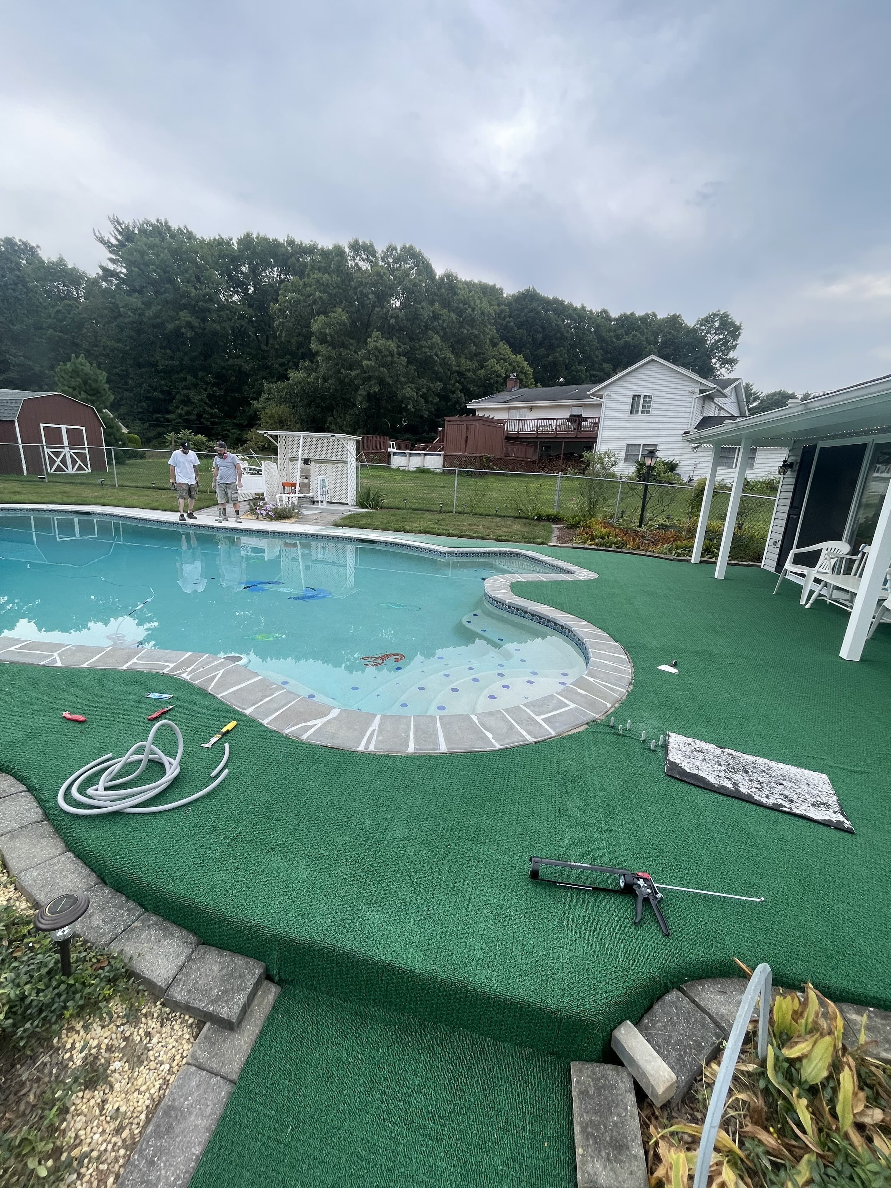 Pool patio area before renovation with worn green surface.