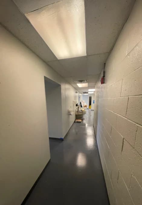 Corridor with light painted walls, a painted block wall and dark floor surfaces.