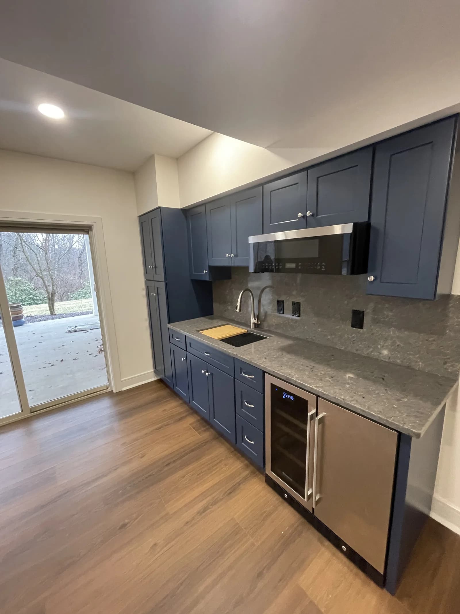 Kitchen with navy cabinets, a patterned gray countertop and a full-height backsplash.